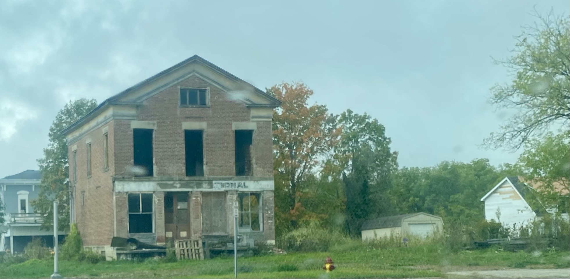 Abandoned brick house with overgrown surroundings