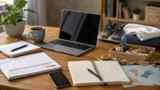 A laptop sits on a wooden table with notebooks, a planner, craft supplies, exercise shoes, and a yoga mat, showing ways to move forward while unemployed.